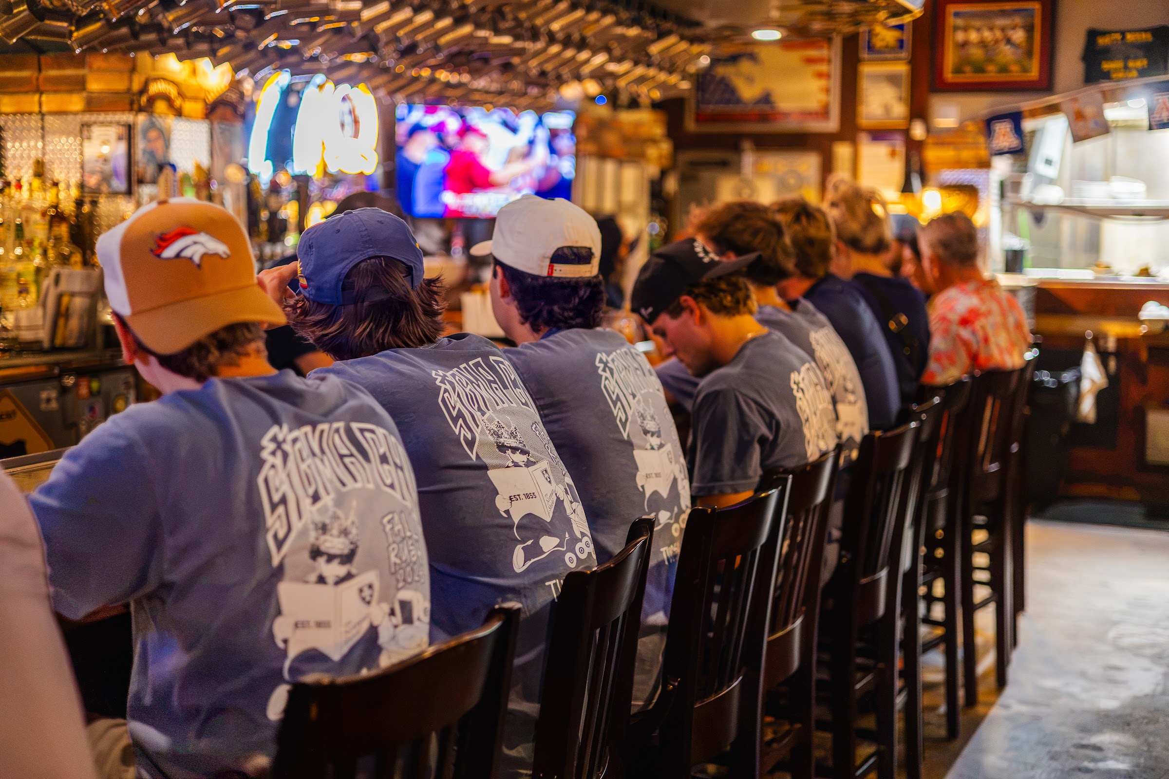 Regulars lined up at the bar in matching shirts, watching the game